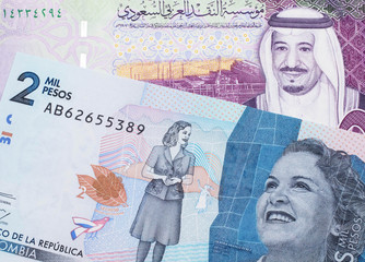 A colorful five Saudi riyal bank note with a blue two thousand peso note from Colombia close up in macro