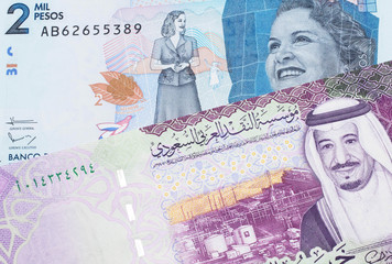 A colorful five Saudi riyal bank note with a blue two thousand peso note from Colombia close up in...