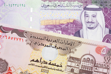 A colorful, five Saudi riyal bank note with a five dirham bank note from the United Arab Emirates close up in macro