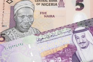 A peach five naira note from Nigeria with a five Saudi riyal bank note close up in macro
