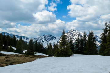 A view on the snowy slopes of Himmeleck in Austrian Alps. There is a massive mountain range in the back, partially covered with snow. Early spring coming to the Alps. Overcast. Achievement and fun