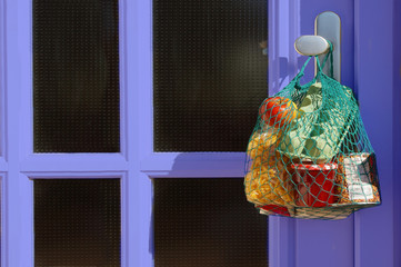delivery during the quarantine. Shopping bag with Merchandise, goods and food is hanging at the...