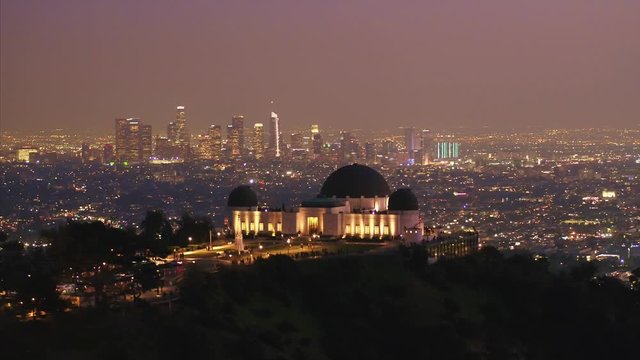Aerial tracking drone shot, of the Griffith Observatory, on Mount Hollywood, at dusk, in Los Angeles, California, USA