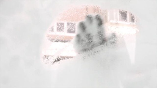 hand of woman cleaning the car window from the snow first using her hand then using a brush