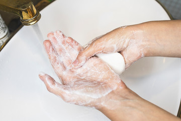 Fototapeta premium Unrecognizable person washing hands, rubbing with soap in sink under water. Hand disinfection. Close up photo. Coronavirus, covid-19, 2019 pandemic prevention. disinfect, sanitize, epidemic concept .
