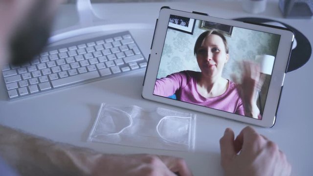 man talking with friend via video call on table spbas waving hand. facetime with wife, girlfriend while coronavirus covid19 2020 epidemic quarantine. medical mask. safety concept