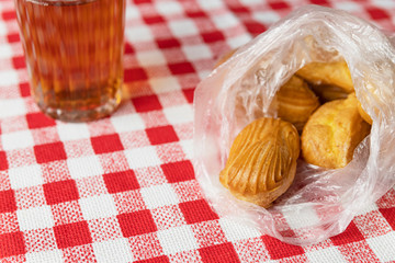 Homemade eclairs on white red checkered tablecloth. Home tea party concept. Tasty sweet pastries