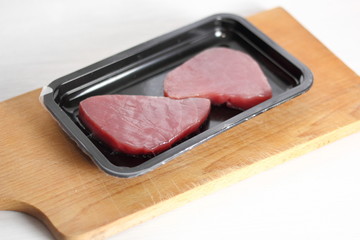 Raw tuna steak in disposable plastic packing box