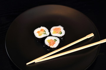 Sushi futomaki with smoked salmon on black plate