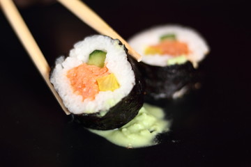 Sushi futomaki with smoked salmon on black plate