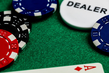 A large copy space on a green felt gaming surface, surrounded by close-up red, blue and black betting chips, a dealer chip and the edge of an ace of diamonds standard playing card.