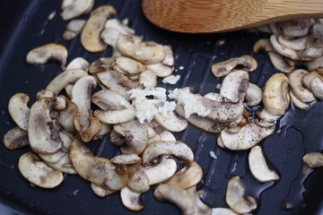 Crushed garlic with fried champignon mushroom in skillet