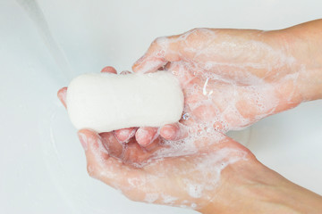 Fototapeta premium Man or woman washing hands, rubbing with soap in sink under water. Hand disinfection. Close up photo. Coronavirus, covid-19, 2019 pandemic prevention. disinfect, sanitize, epidemic concept .