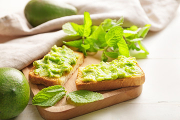 Board with tasty avocado sandwiches on table
