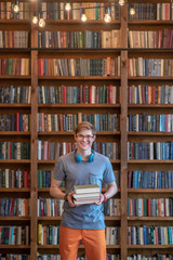 Fair-haired young man in eyeglasses standing in the library