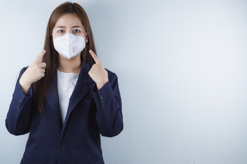 The business woman wearing protection face mask against coronavirus, PM 2.5 and cold, and her finger point on her mask.