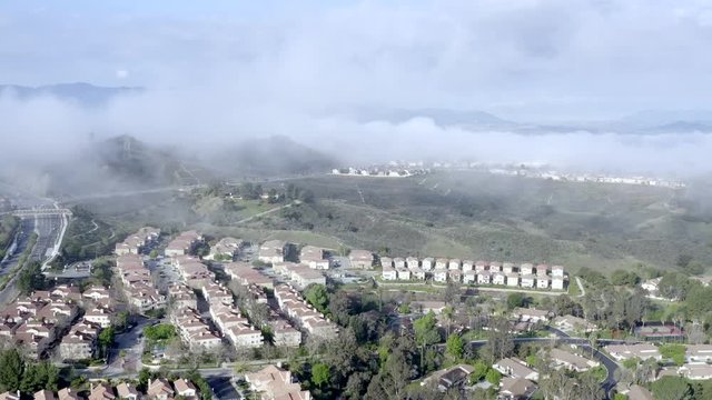 Aerial push view, morning fog over neighborhood of houses