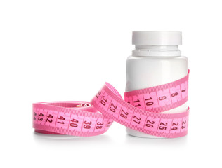 Bottle with weight loss pills and measuring tape on white background