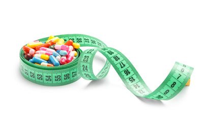Weight loss pills with measuring tape on white background