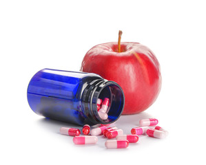 Bottle with weight loss pills and apple on white background