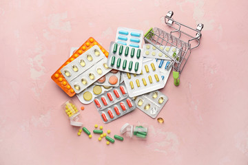 Small shopping cart with pills on color background