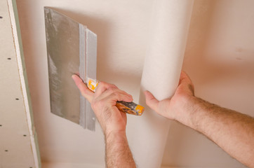 The Builder puts plaster on the wall.Hand holding a spatula with construction mix and smoothes out...