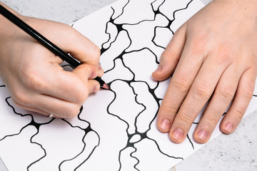 Man is drawing an abstract imaginary picture of curves by a black pencil in his hand. A psychological art therapy tests. Identification of the unconscious, subconscious, the depths of the human brain.