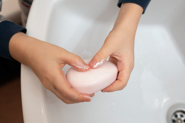 close-up child soaping his hands with soap in bathroom