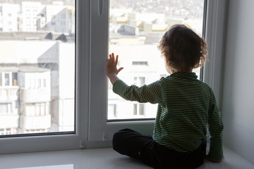 a boy dreams of going out sitting on quarantine at home by the window