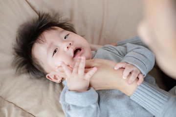 Close up of parent's hand is applying topical cream to the baby for skin care on the bed