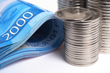 Piles of Russian coins and a banknote of 2000 rubles are very close-up. News about the Russian economy, investments, recession, banks, deposits, inflation, devaluation, the dollar exchange rate. Macro