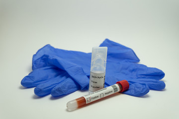Coronavirus vaccine surrounded by a glove and a blood test.  The blood tube is labeled positive 2019-NcOv.