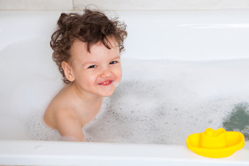 Cute baby is washing in bath. The symbol of purity and hygiene education.