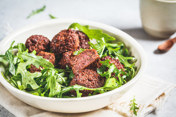 Beetroot Falafel with arugula leaves in a white bowl. Healthy vegan food concept.
