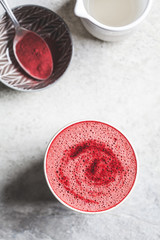 Pink beetroot latte with milk and beetroot powder in a ceramic glass, top view.