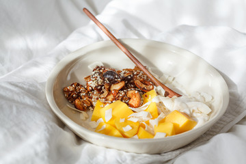 Breakfast in bed - homemade granola, yogurt and mango in bowl.