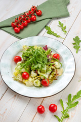 Healthy vegetable salad with cheese and cherry tomatoes. Lunch menu of food restaurant on white wooden background in rustic style, side view