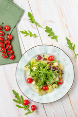 Healthy vegetable salad with cheese and cherry tomatoes. Lunch menu of food restaurant on white wooden background in rustic style, top view