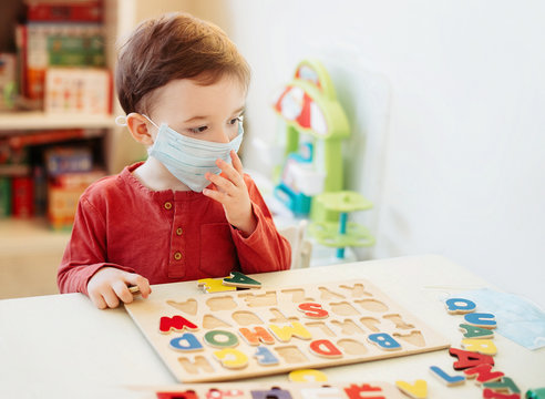 Little boy in medical mask playing letters. He coined the word coronovirus.