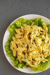 Homemade Coronation Chicken Salad on a white plate on a gray surface, top view. Flat lay, from above, overhead.