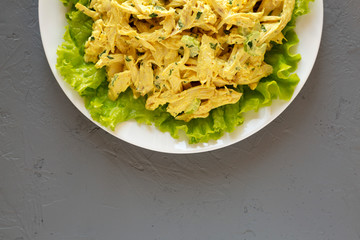 Homemade Coronation Chicken Salad on a white plate on a gray surface, overhead view. Flat lay, from above, top view. Copy space.