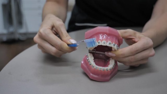 woman shows how to brush teeth with braces