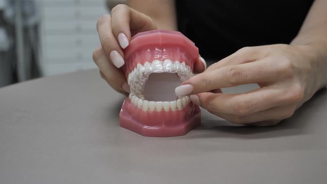 Woman showing how teeth with Invisalign looks on a teeth model