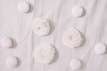 Fototapeta na wymiar Spring wallpaper. Pink rose flowers and marshmallows on a white background. Flowers composition. Flat lay, top view, copy space. 