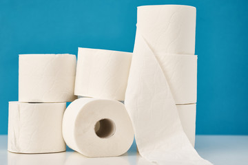 Stacked toilet paper rolls on a blue background. Hygiene concept