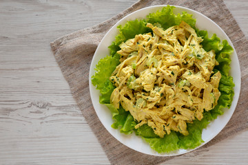 Homemade Coronation Chicken Salad on a white plate, overhead view. Flat lay, from above, top view....