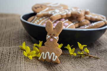 Easter holiday cookies servet on dish on the table with jute tablecloth, group of color painted gingerbread sweets springtime