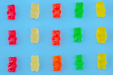 Delicious bright colored jelly bears on a blue background laid out in the same order, top view