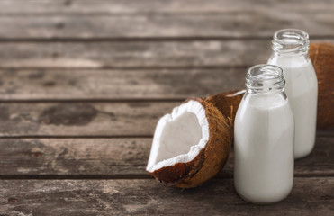 Fototapeta na wymiar Coconut milk in bottles on wooden table. Healthy eating concept