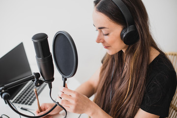 Woman blogger recording radio podcast in studio.